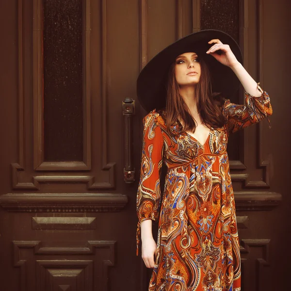 Portrait of a beautiful girl in a dress with a hat at the door — Stock Photo, Image