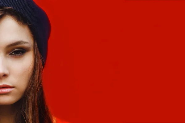 Portrait of a beautiful girl in hat and striped sweater on a red — Stock Photo, Image