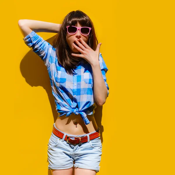 Portrait of a beautiful surprised girl in blue shirt and glasses on a background of orange wall — Stock Photo, Image