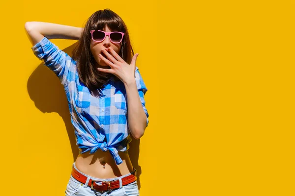 portrait of a beautiful surprised girl in blue shirt and glasses