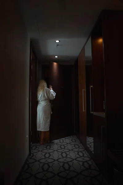 Blonde vrouw met badjas opent een deur — Stockfoto
