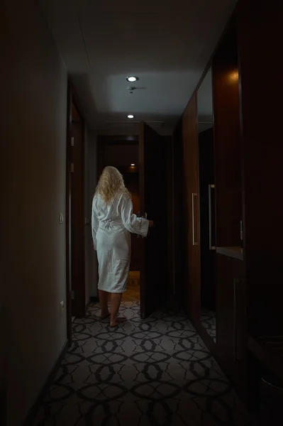 Frau im weißen Bademantel öffnet die Tür — Stockfoto