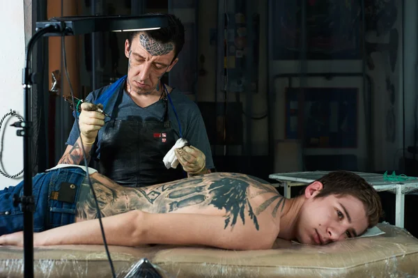 Tattoo artist looks at the result — Stock Photo, Image
