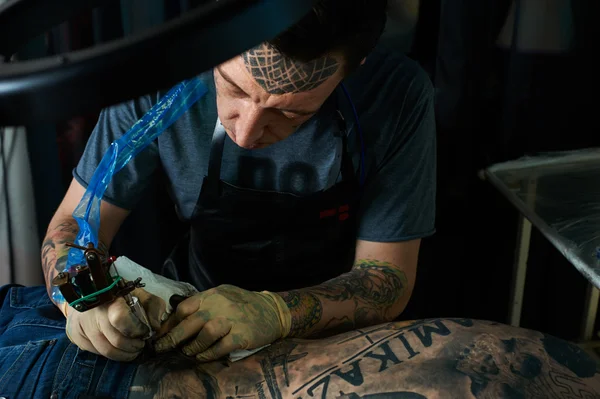 Maestro del tatuaje termina un tatuaje en la espalda —  Fotos de Stock