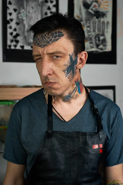 Татуированный человек в кожаном фартуке строит рожи — стоковое фото