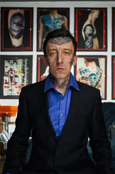Татуировщик в черной куртке и синей рубашке в студии — стоковое фото