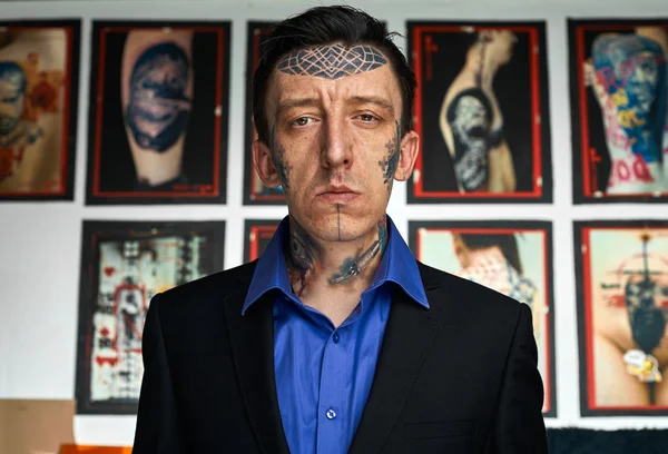 Uomo con tatuaggi sul viso in giacca e camicia nera — Foto Stock
