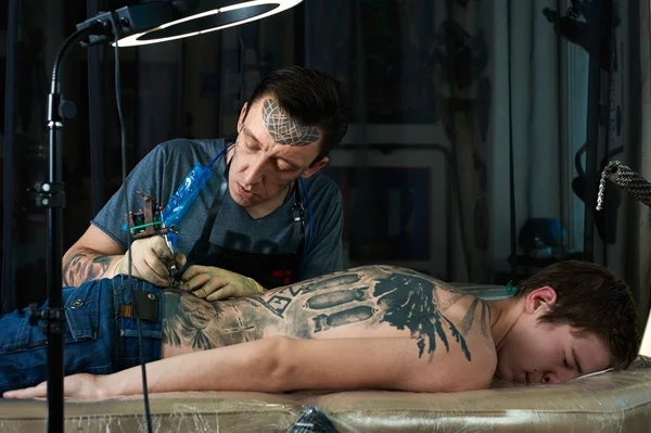 Tattooist makes a tattoo on the back — Stock Photo, Image