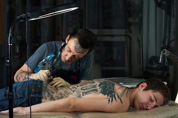 Татуировщик делает татуировку на спине — стоковое фото