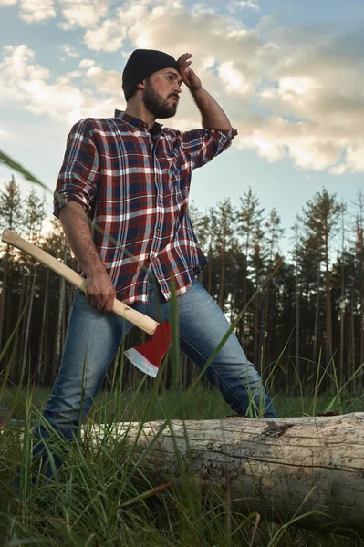 Vousatý dřevorubec drží velký ax v jedné ruce a maže sw — Stock fotografie