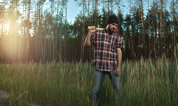 Skäggiga skogshuggare i hatt innehar en stor yxa på axel — Stockfoto