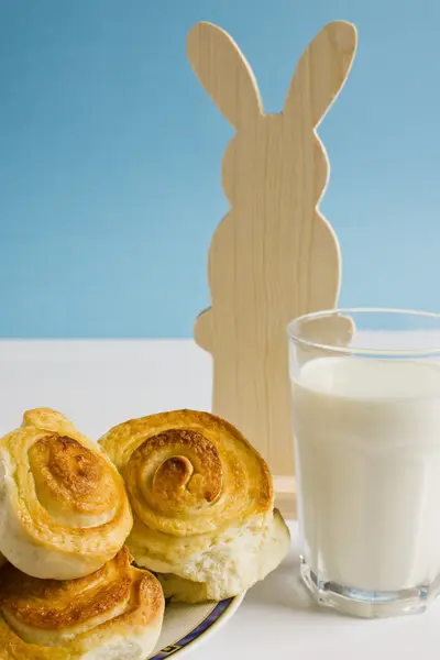 Colazione con panini alla cannella e bicchiere di latte su sfondo blu con decorazione coniglietto pasquale. Cottura fatta in casa a Pasqua . — Foto Stock