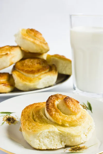 Colazione con panini alla cannella e bicchiere di latte su sfondo bianco. Cottura fatta in casa . — Foto Stock