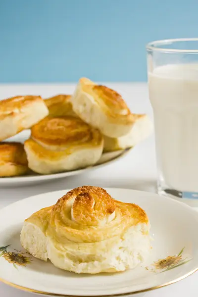 Colazione con panini alla cannella e bicchiere di latte su sfondo blu. Cottura fatta in casa . — Foto Stock