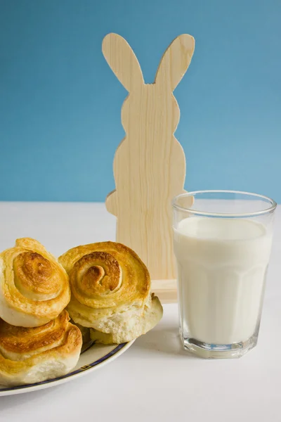 Colazione con panini alla cannella e bicchiere di latte su sfondo blu con decorazione coniglietto pasquale. Cottura fatta in casa a Pasqua . — Foto Stock