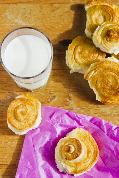 Breakfast with cinnamon buns and glass of milk on wooden table. Homemade baking.