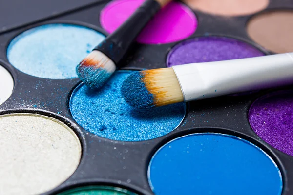 Pinsel für Make-up auf den Lidschattenpaletten. Textur aus bröselig blau funkelnden Schatten. — Stockfoto