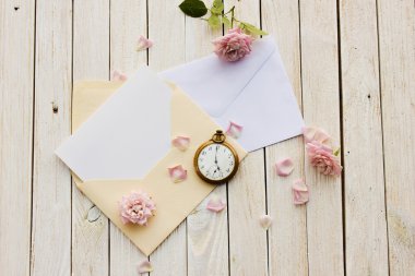 İçinde kart olan iki zarf, eski cep saati ve bir gül