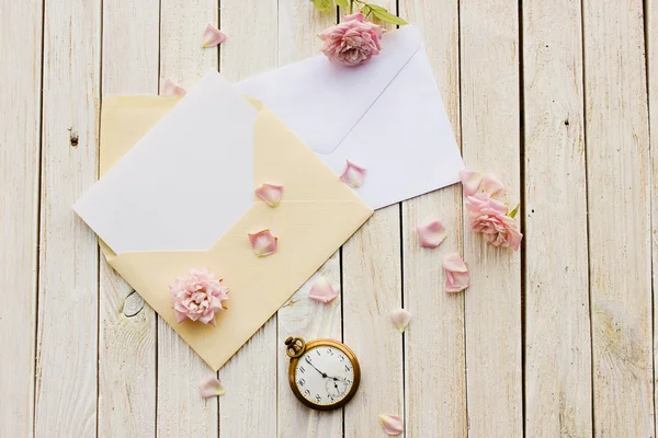 İçinde kart olan iki zarf, eski cep saati ve bir gül