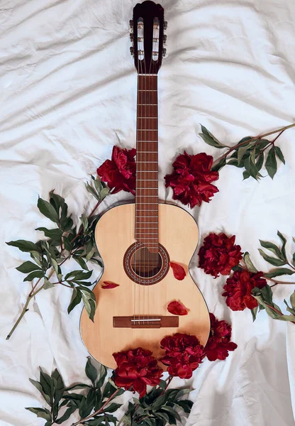 Una Chitarra Acustica Legno Giace Lenzuolo Bianco Circondato Peonie Rosse — Foto Stock