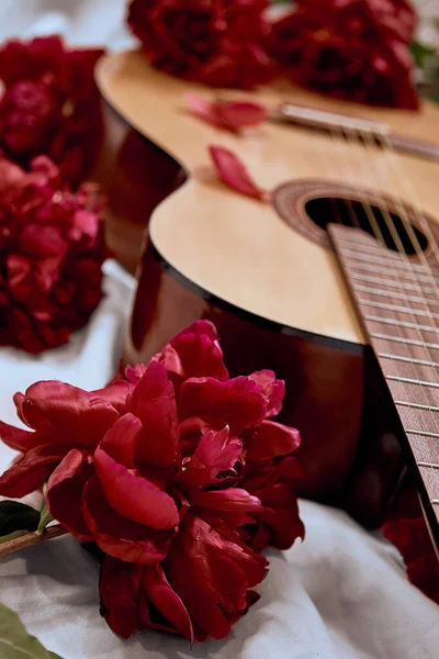 Una Chitarra Acustica Legno Giace Lenzuolo Bianco Circondato Peonie Rosse — Foto Stock