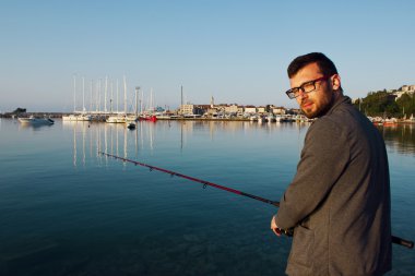 Genç bir adam denizde balıklar. Balıkçı iplik ile. Deniz balıkçılığı.