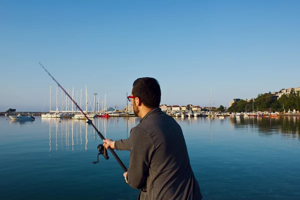 Genç bir adam denizde balıklar. Balıkçı iplik ile. Deniz balıkçılığı.