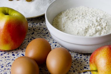 Mutfak masasında elmalı turta için malzemeler. Un, şeker, Kuru üzüm, yumurta ve ev yapımı hamur işleri için elma.