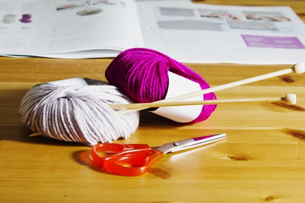 Strickzubehör auf einem Holztisch. Wollknäuel und Stricknadeln aus Holz auf dem Tisch. — Stockfoto