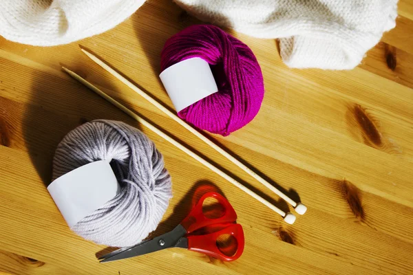 Knitting accessories on a wooden table. Balls of wool and wooden knitting needles on the table. — Stock Photo, Image