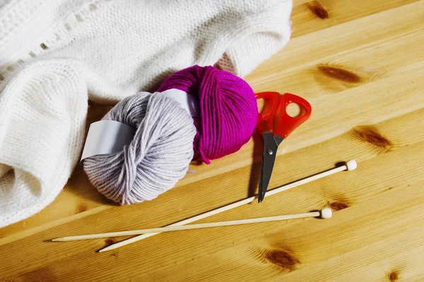 Strickzubehör auf einem Holztisch. Wollknäuel und Stricknadeln aus Holz auf dem Tisch. — Stockfoto