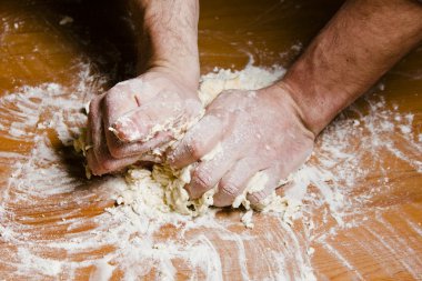 Erkekler el ahşap masa üzerinde hamur yoğurmak. Şef hamur için İtalyan yemekleri hazırlar..