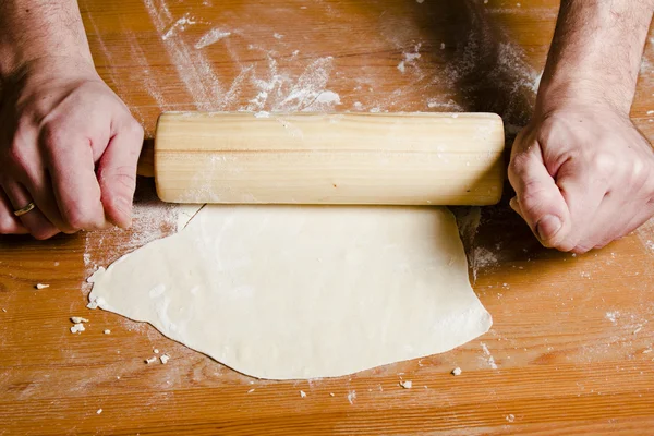 Pâte roulée mains d'homme avec rouleau à pâtisserie en bois sur la table en bois . — Photo