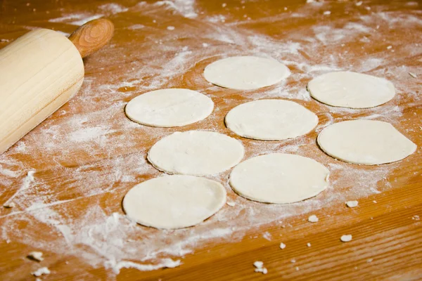 Mantı, mantı, tortellini ahşap bir masa üzerinde hazırlıkları. Hamuru Kurabiye Pişirme için yuvarlak kütük.