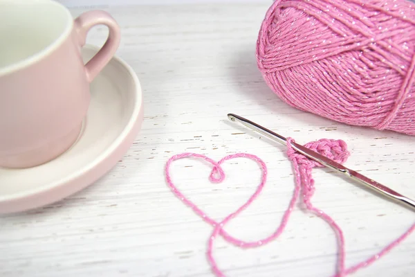 Roze haak achtergrond met garen hart en koffie beker — Stockfoto