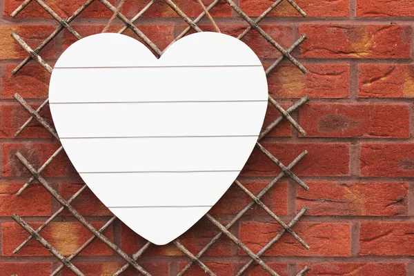 Cuore di legno bianco su muro di mattoni. Copia spazio — Foto Stock