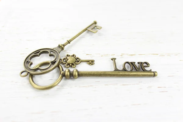 Amore Tre chiavi in ottone su uno sfondo di legno bianco angosciato — Foto Stock