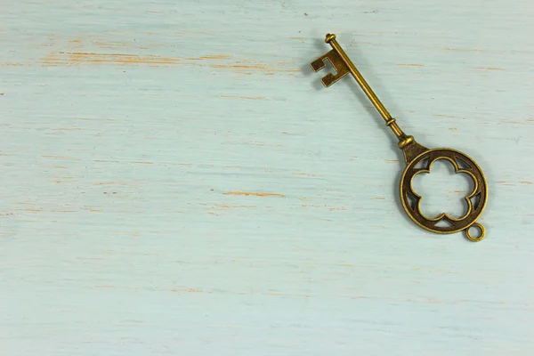 Antique brass key on a pale green distressed wood background. — Stock Photo, Image