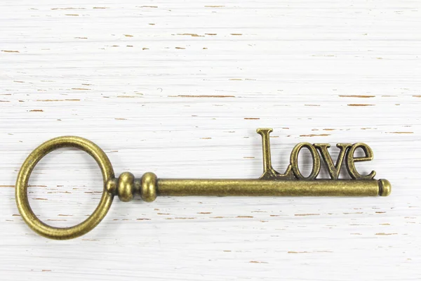 Klucz do klucz miłość mosiądz na białym tle drewniane — Zdjęcie stockowe