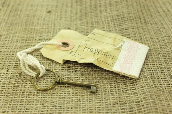 Mutluluk kavramı rustik arka plan üzerinde anahtarı — Stok fotoğraf