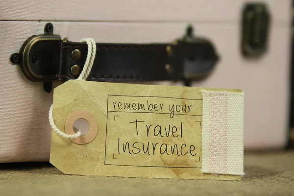 Travel insutance tag on vintage suitcase Stock Image