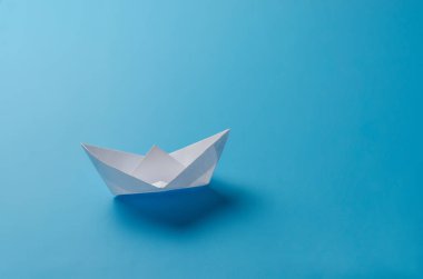 Mavi arka planda beyaz kağıt tekne