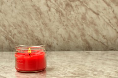Kırmızı mum mermer masada yanıyor..