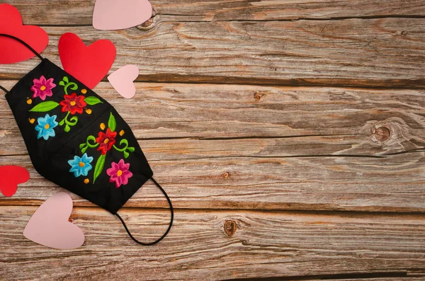 Hearts and facial mask on wooden table. celebration of valentine's day in times of virus