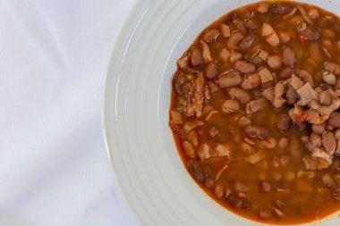 Masada beyaz masa örtüsüyle servis edilen fasulye tabağı. Geleneksel Meksika yemekleri.