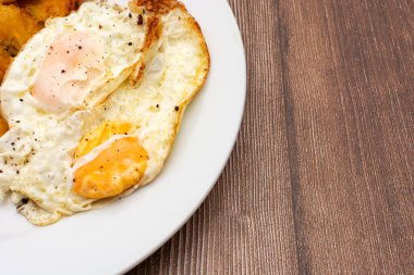 Ahşap masada kızarmış yumurta tabağı. Fotoğrafın köşesindeki levha..
