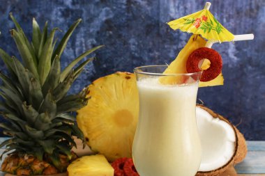 Pina colada, tropikal kokteyl. Bir bardak pina colada mavi ahşap bir masa üzerinde kokteyl bileşenleri arka planda.