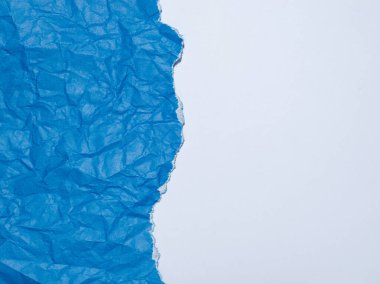 Kırışmış ve yırtılmış mavi kağıt beyaz arka planda.