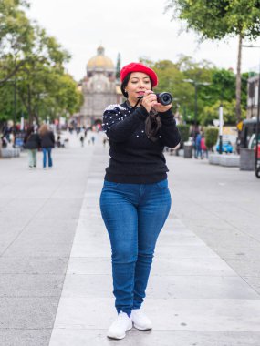 Kızıl bereli Çekici Kadın Meksiko 'da elinde bir kamera tutuyor.