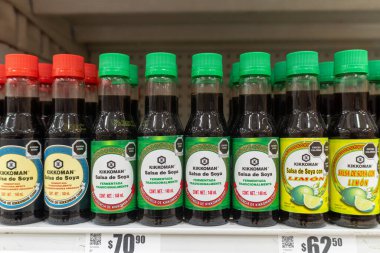 Villa de Alvarez, Colima, Meksika. 20 Ekim 2025: Bir süpermarketin rafında kırmızı ve yeşil şapkalı bir sürü Kikkoman marka soya sosunun yakın plan çekimi.